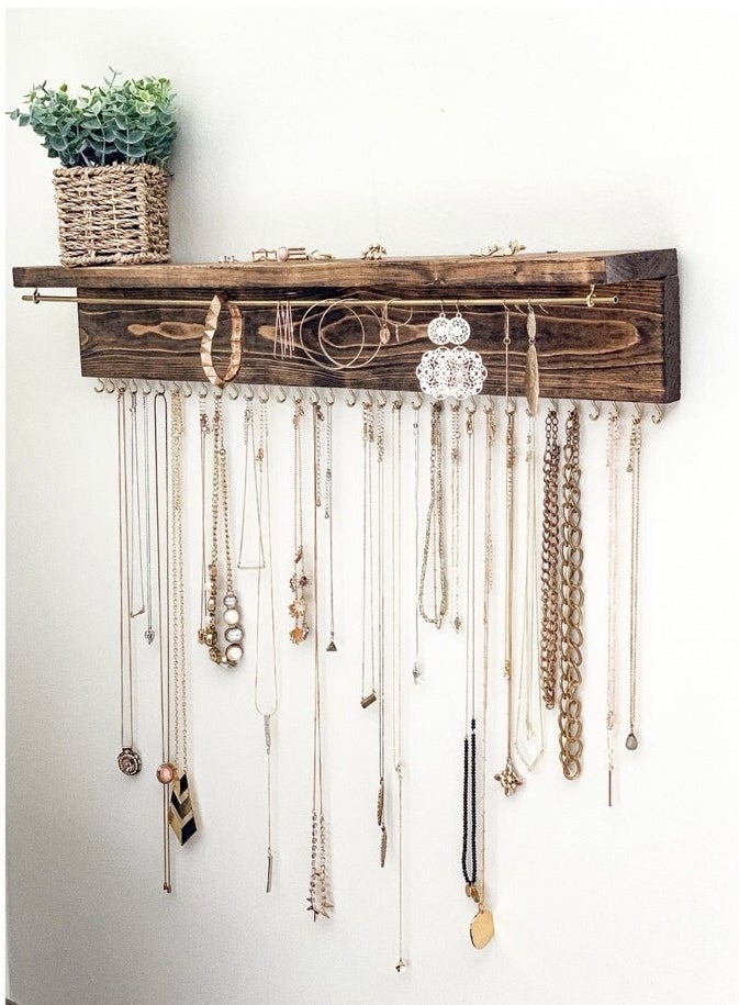 necklaces and other jewlery hanging from the wooden organizer on a wall
