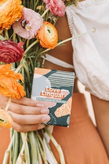 A model holding the game behind their back with a bundle of flowers