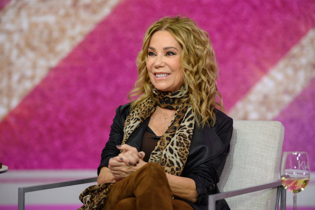 Kathie Lee Gifford sitting and smiling with legs crossed