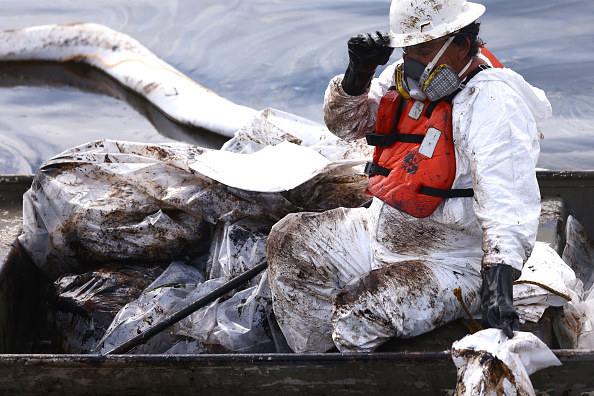 A worker in a protective suit, headgear, and respirator cleans oil in the Talbert Marsh wetlands in Huntington Beach, California