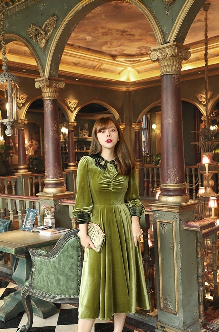 model in green midi with long sleeves, statement collar and cuffs and ruching at the bust