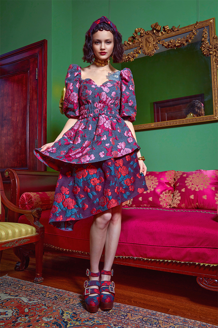 model in purple, blue, and red rose brocade asymmetric dress with puffed sleeves and smocked waist