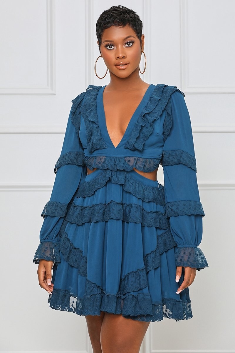 Model in teal blue mini with long sleeves and lace trim and cutouts at the waist