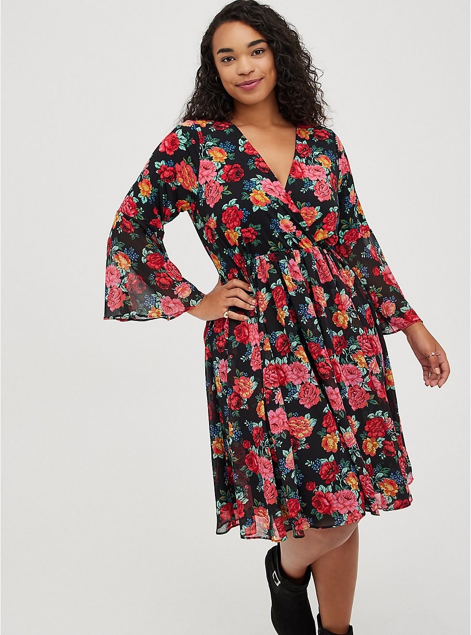model in knee length black dress with colorful floral print and long flared sleeves