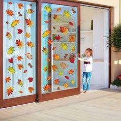 A child pushing a sliding door with window clings in green, orange, red, and brown