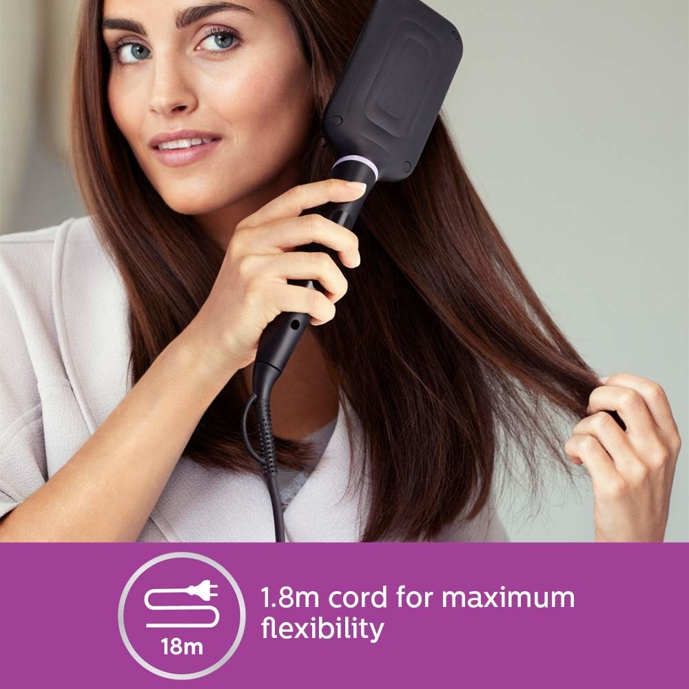 A woman straightening her hair with the hot air brush