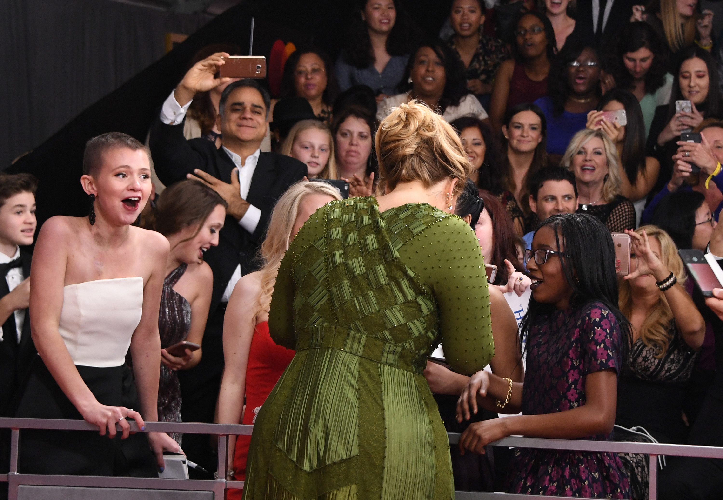 Adele greets a group of fans and signs autographs