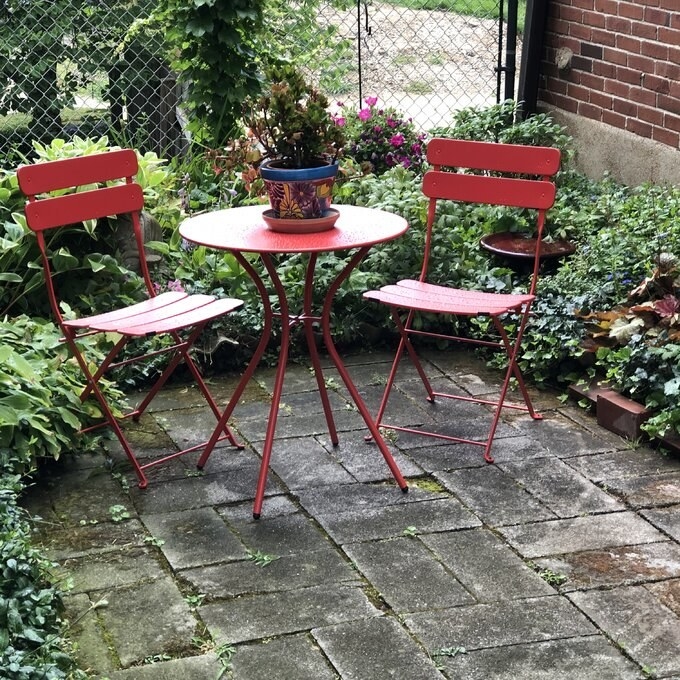 A reviewer&#x27;s photo of the red bistro set in their garden patio