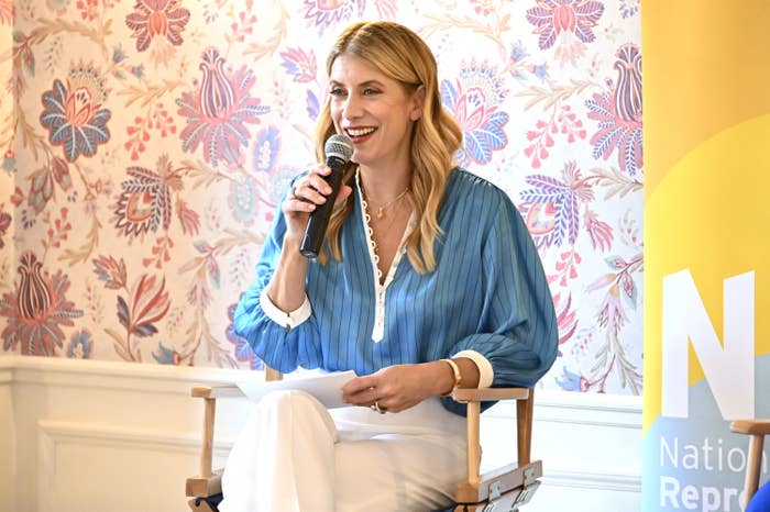 A smiling Kate sitting and speaking into a microphone