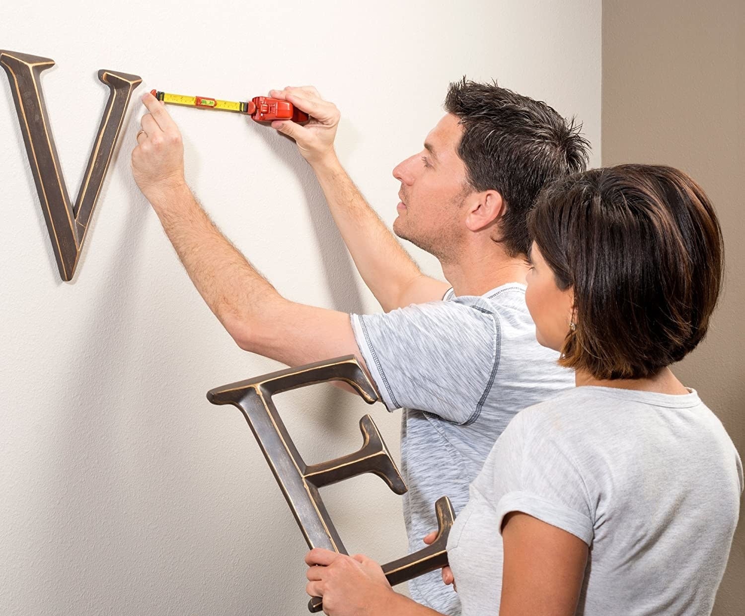 A couple of people using the tool to hang some wall decor