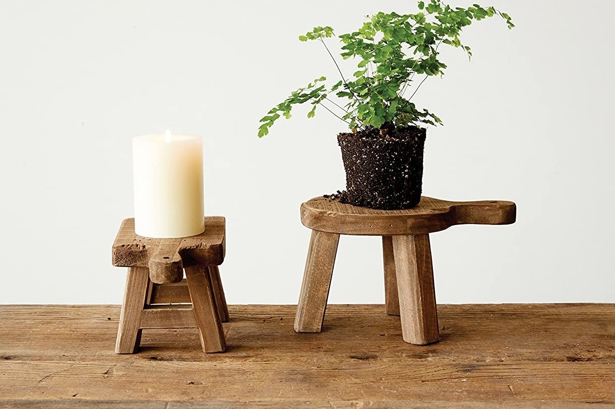 a pair of rustic stools holding a candle and a plant