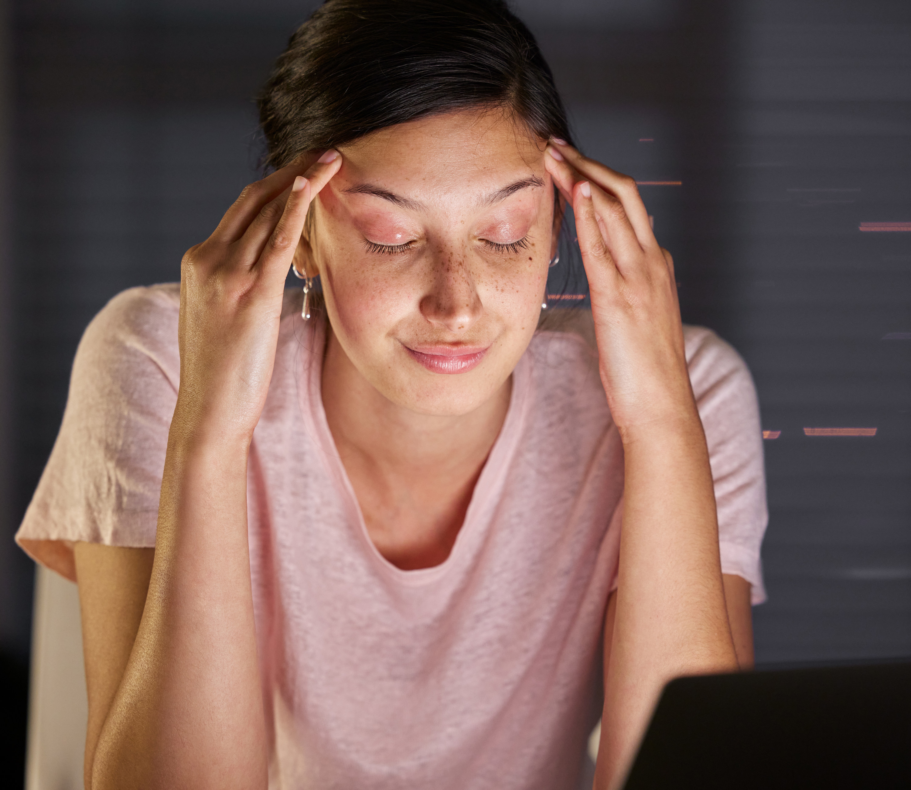 Woman rubbing her temples at her desk