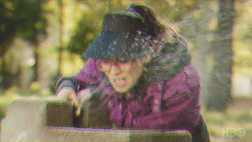 Woman with visor on drinks water out of a fountain