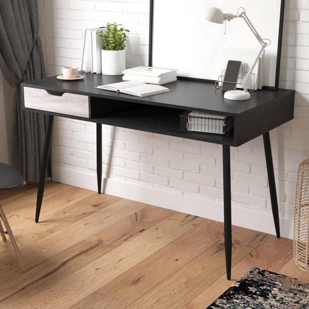 A black desk with a light wood drawer.