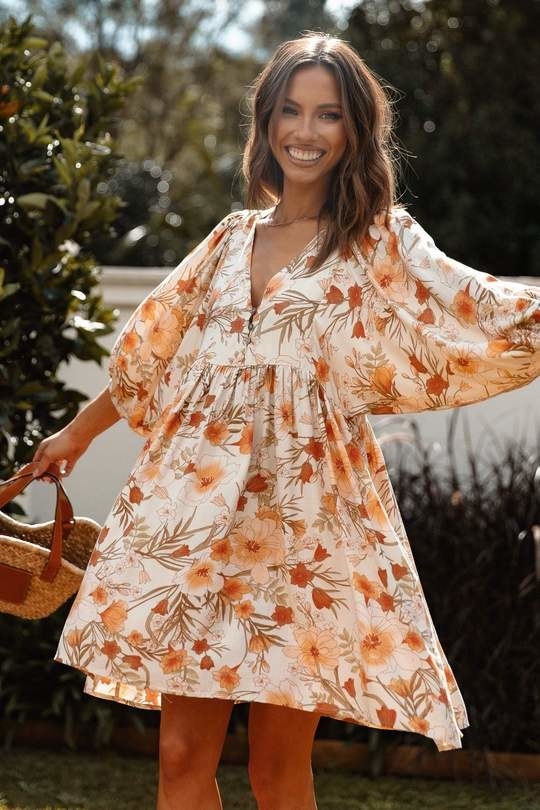 model in white and orange floral print elbow-sleeve dress that hits above the knee
