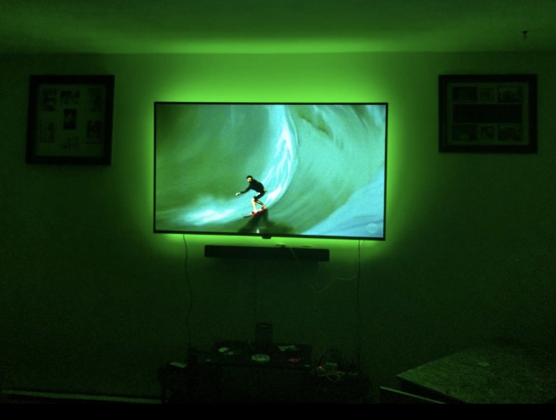 Green LED lights around television screen on wall