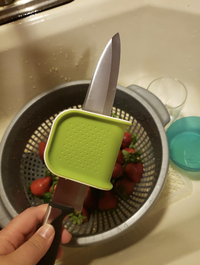Knife cleaner scrubbing knife over a bowl of strawberries