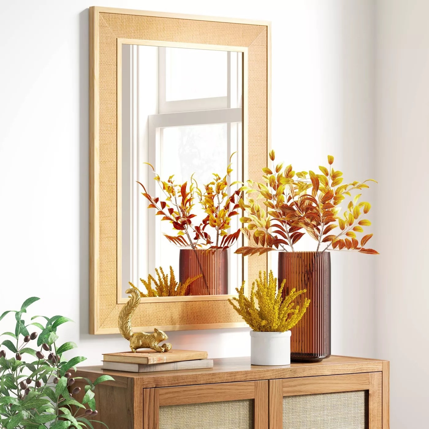 The rectangular mirror with a rattan frame hanging above a cabinet