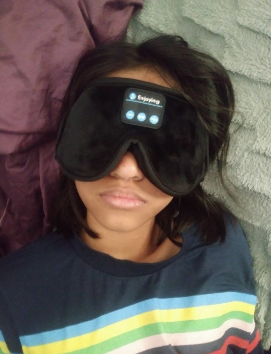 Woman wearing black eye mask while laying down