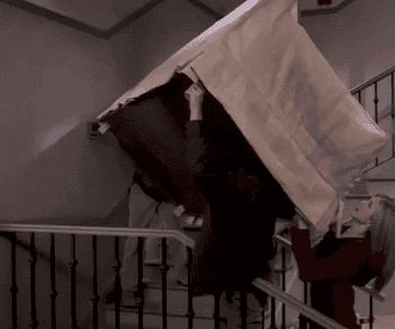 A gif from Friends where ross rachel and chandler are trying to get a couch up the staircase