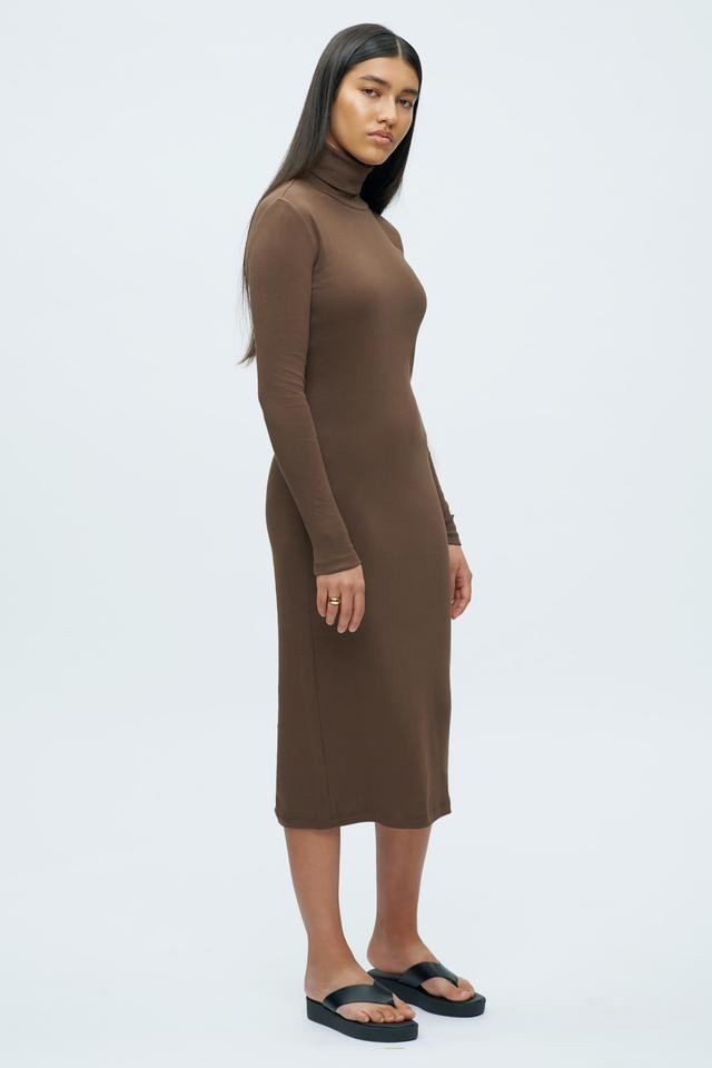A person wearing a long sleeved turtleneck dress with flip flops