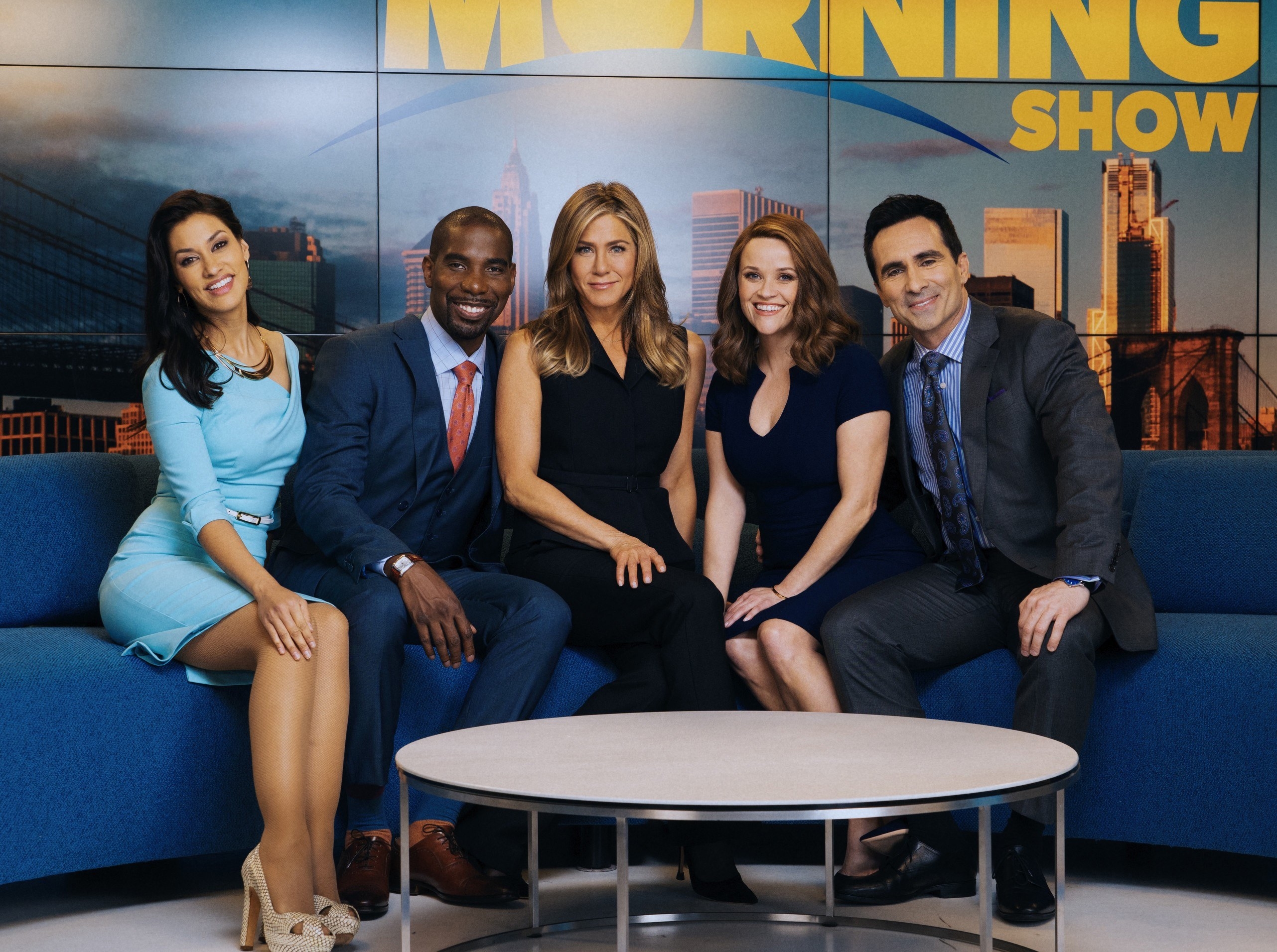 Janina Gavankar, Desean Terry, Jennifer Aniston, Reese Witherspoon, and Nestor Carbonell sit on the couch of The Morning Show