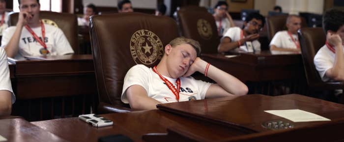 A boy falls asleep at a desk in the Texas State legislature