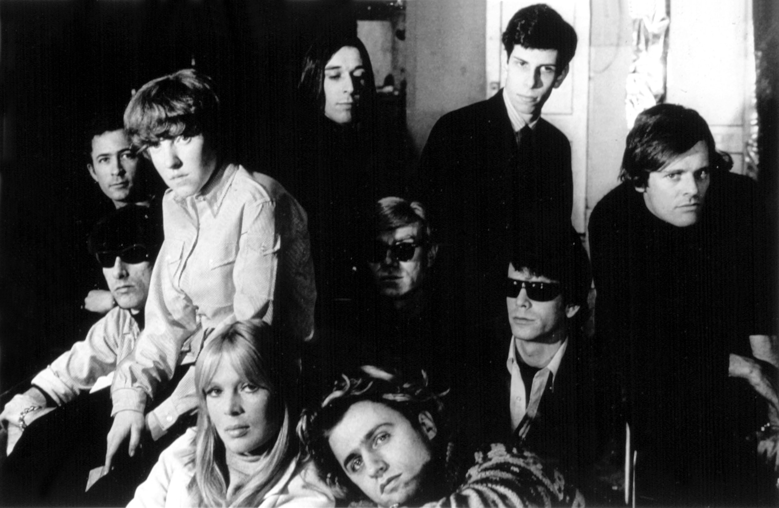 Andy Warhol, Nico, Paul Morrisey, and Gerard Melanga sit together with the members of The Velvet Underground