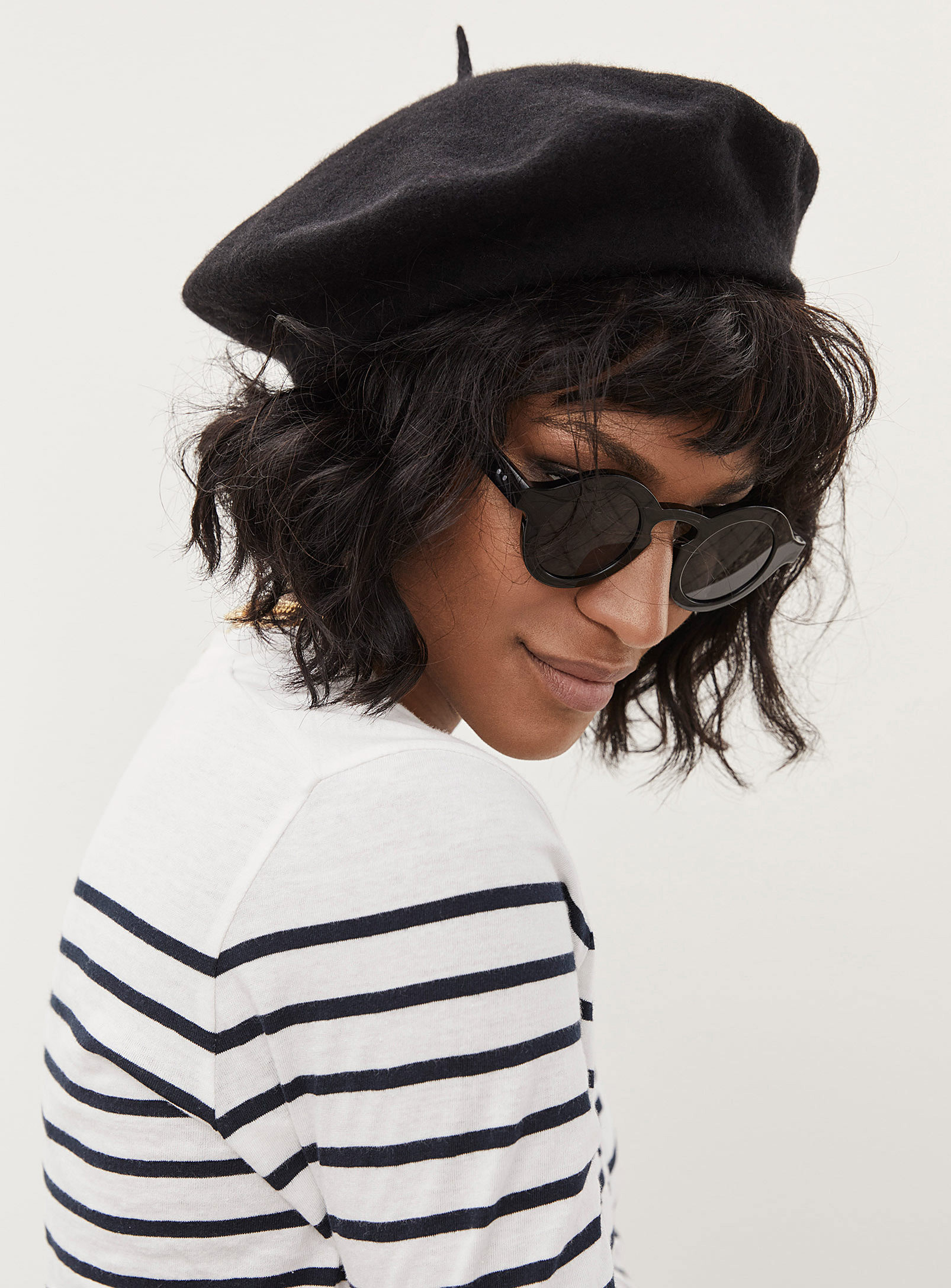 A person wearing a beret with a striped shirt and sunglasses