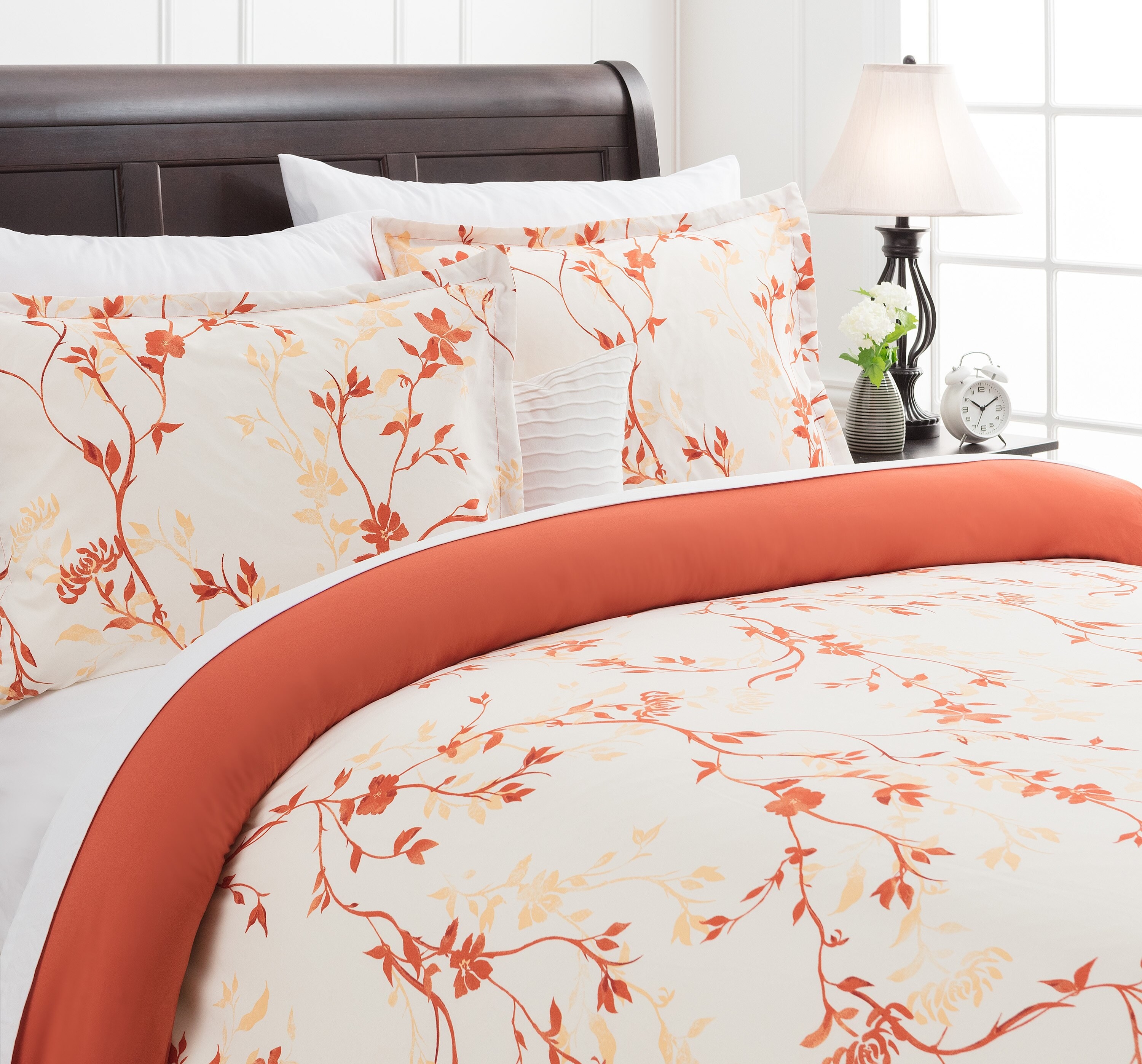 An orange fall floral duvet and matching pillows on a bed