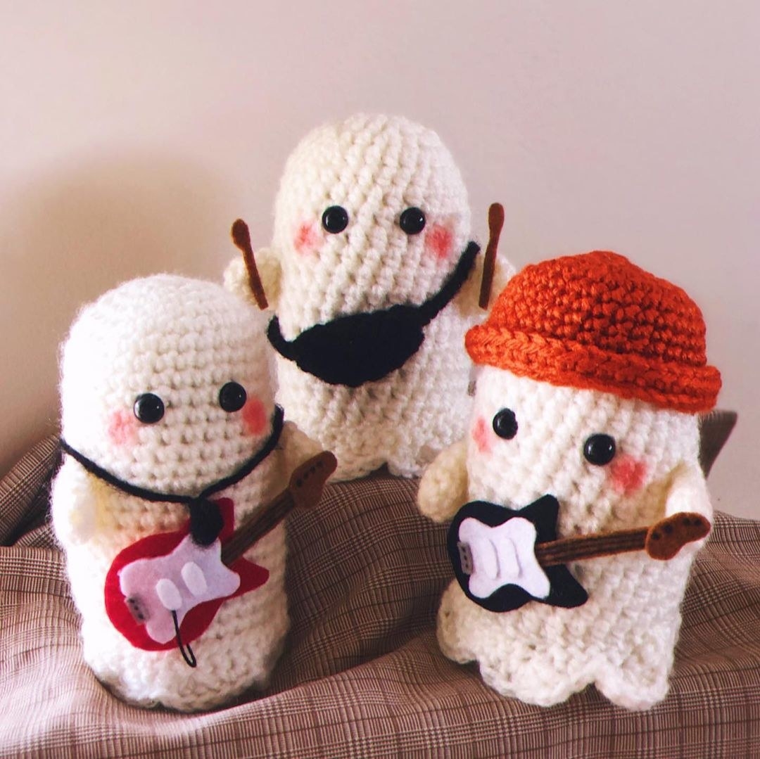 Crocheted plushies, two are holding guitars and one is holding drumsticks.