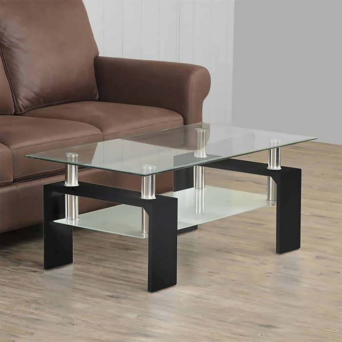 A two-tiered glass top coffee table next to a sofa