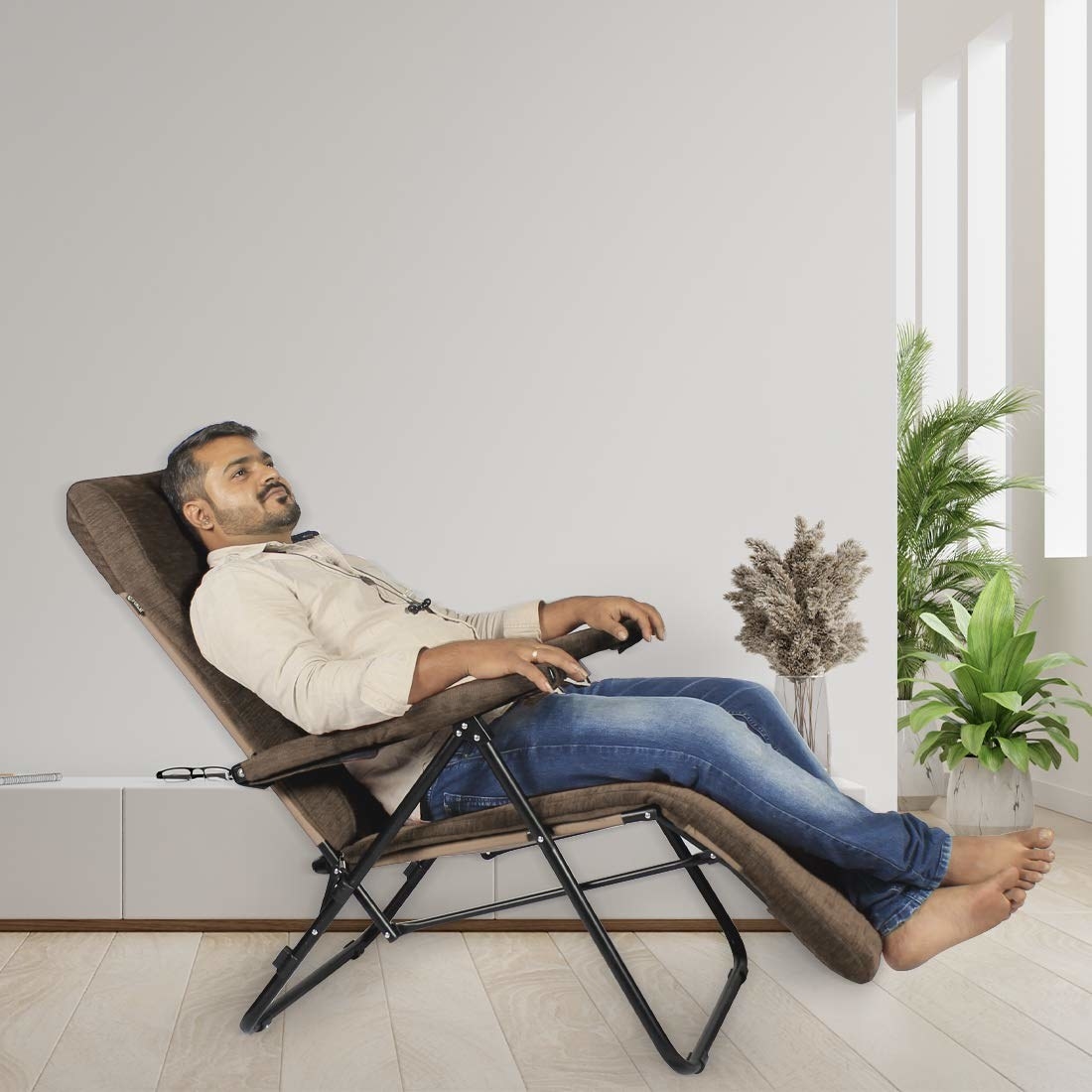 A man laying back on a reclining chair
