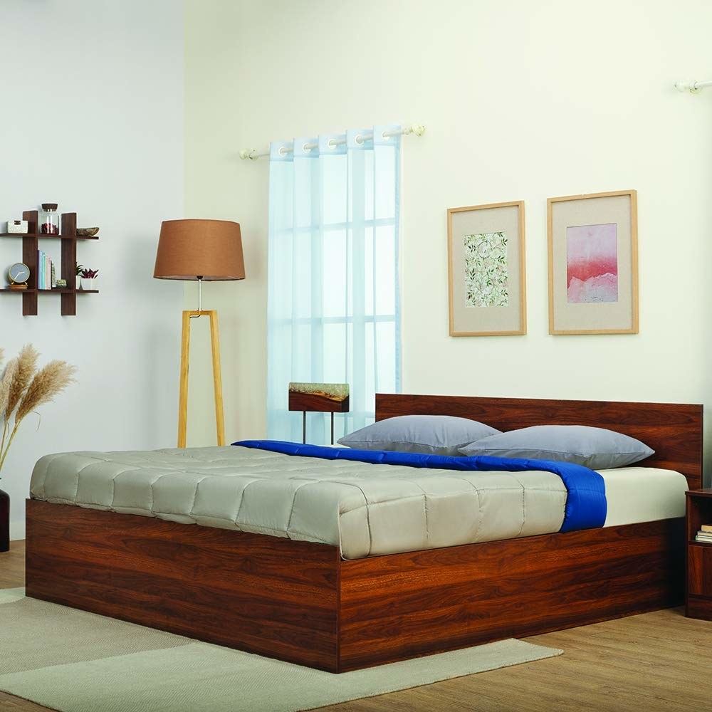 A wooden bed frame that comes with a mattress and a lamp beside it