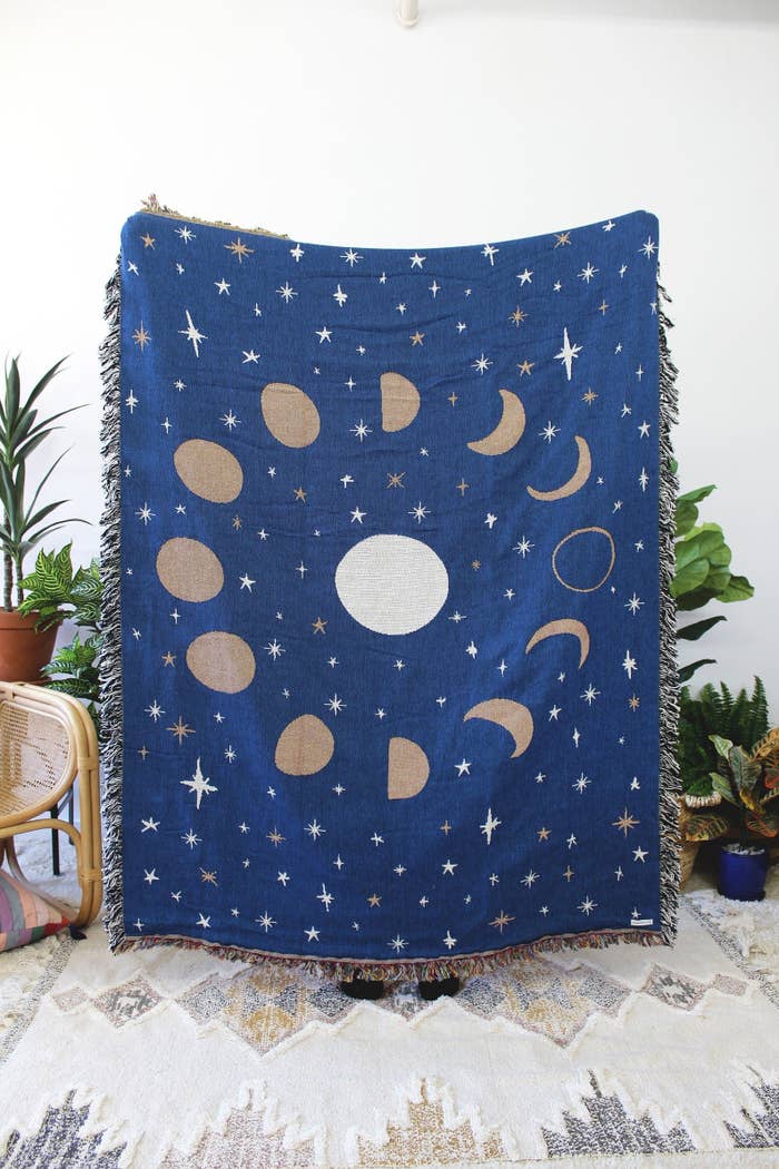 A navy blue cotton throw blanket with a pattern of stars and moons.