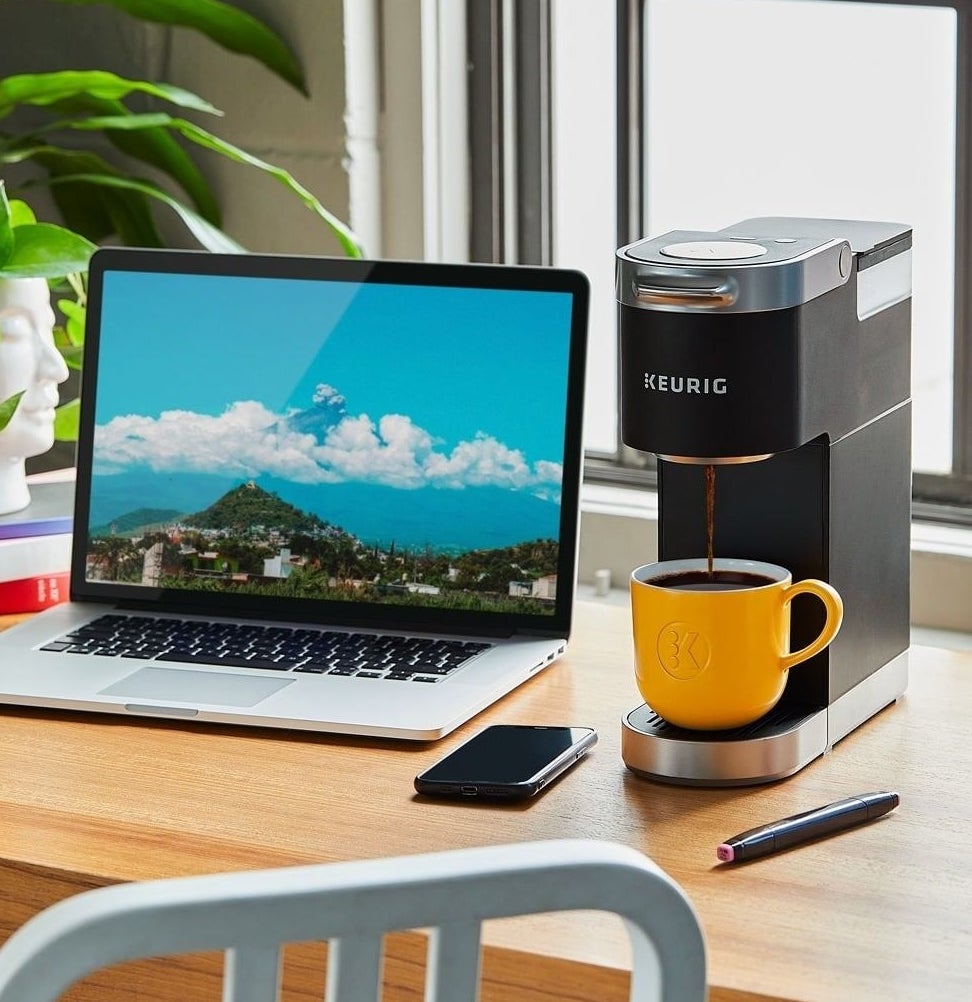 The coffee maker on a desk beside a computer