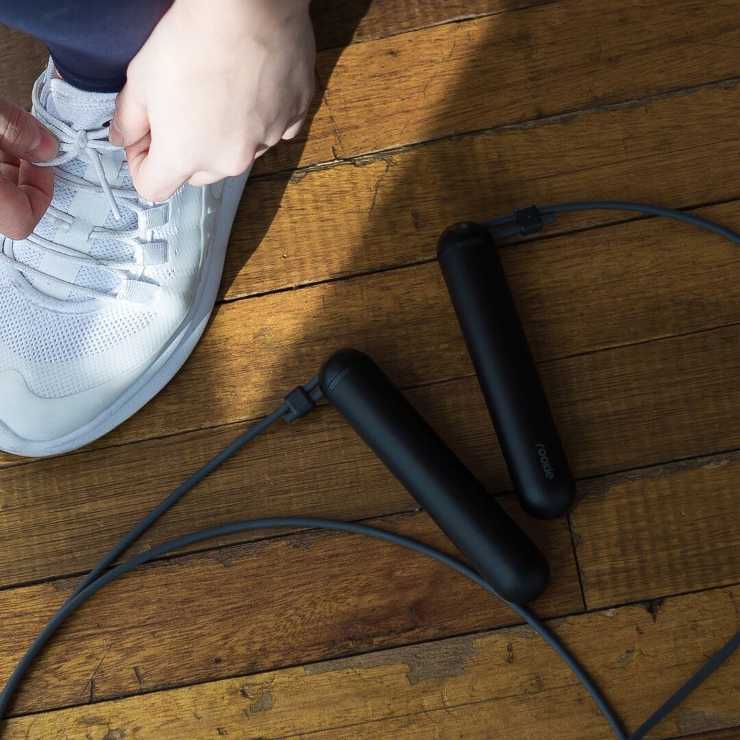 The skipping rope on a hardwood floor beside someone tying their shoe