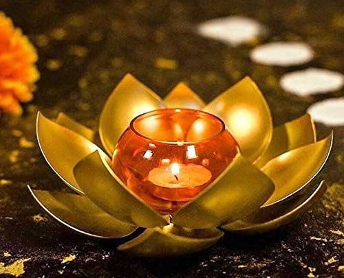 A lotus shaped candle holder with a lit candle in the middle
