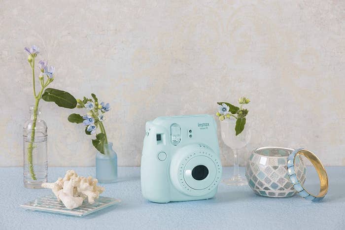 A blue Polaroid camera with a candle beside it