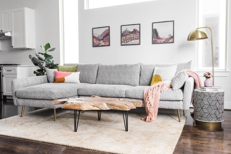 grey sectional couch in a living room with a coffee table, throw pillows, and a pink throw blanket on it