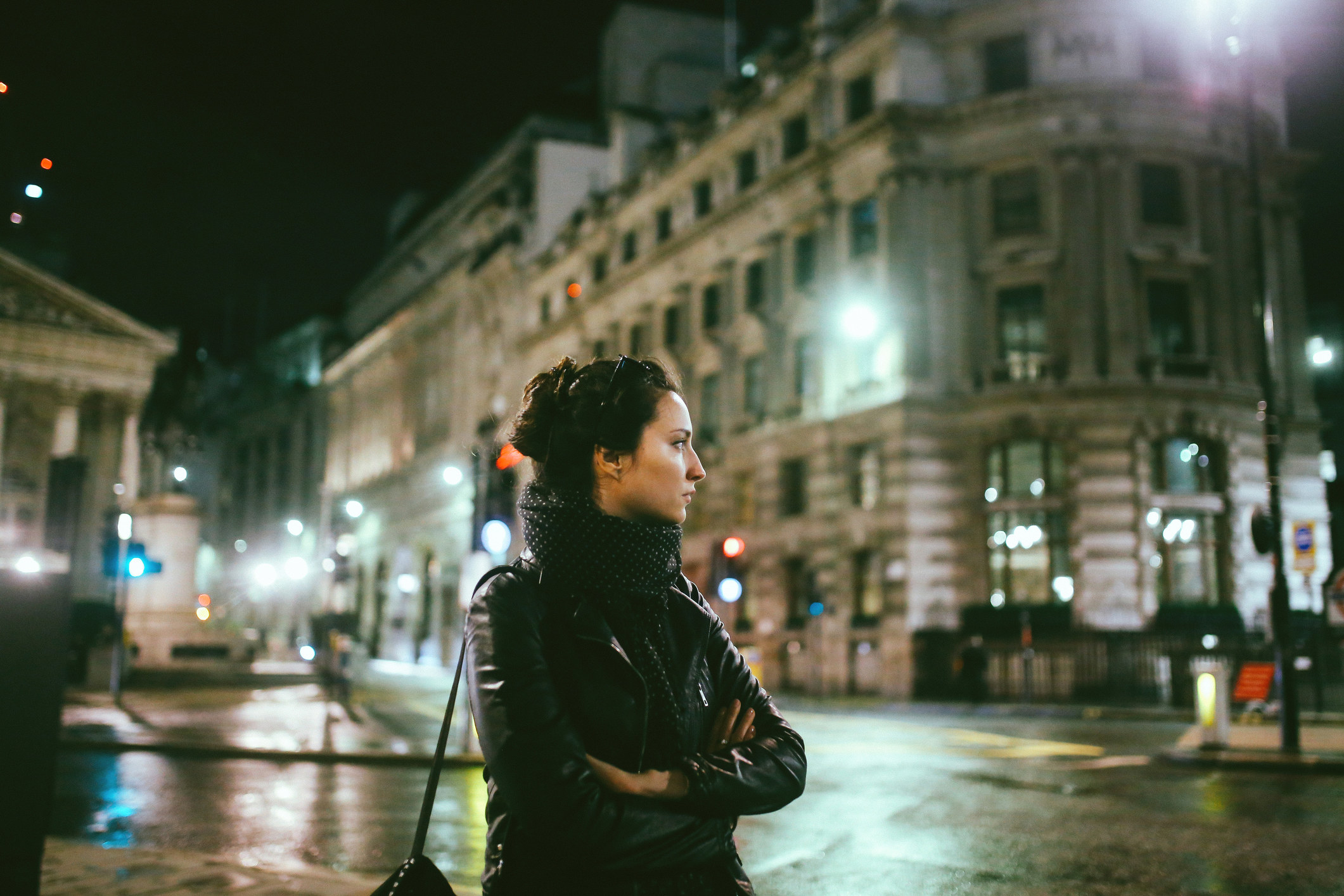 A woman waiting on a street alone at night