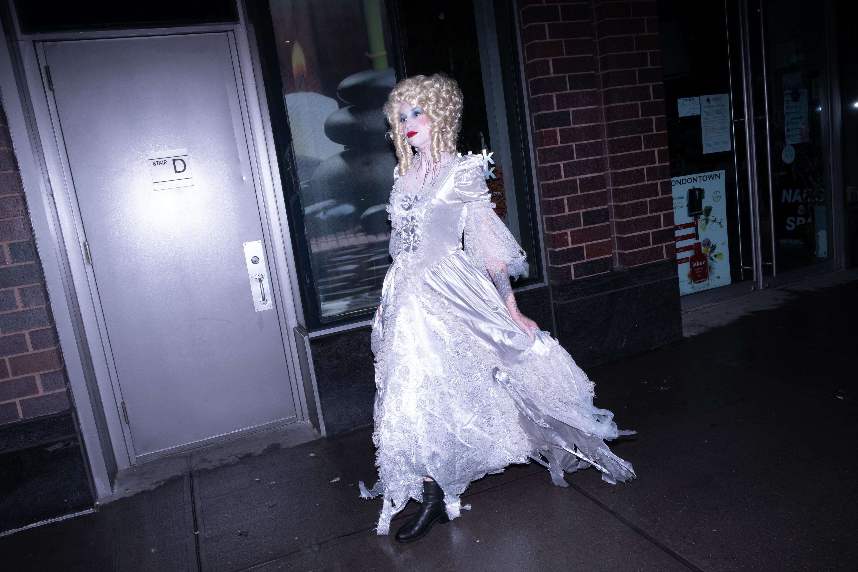 A ghostly marie antoinette walking in front of a door that says stair D on the street