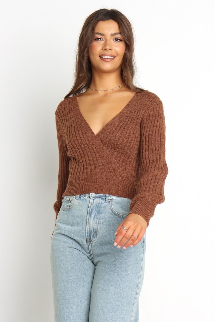 model wearing a wrap style sweater top and jeans