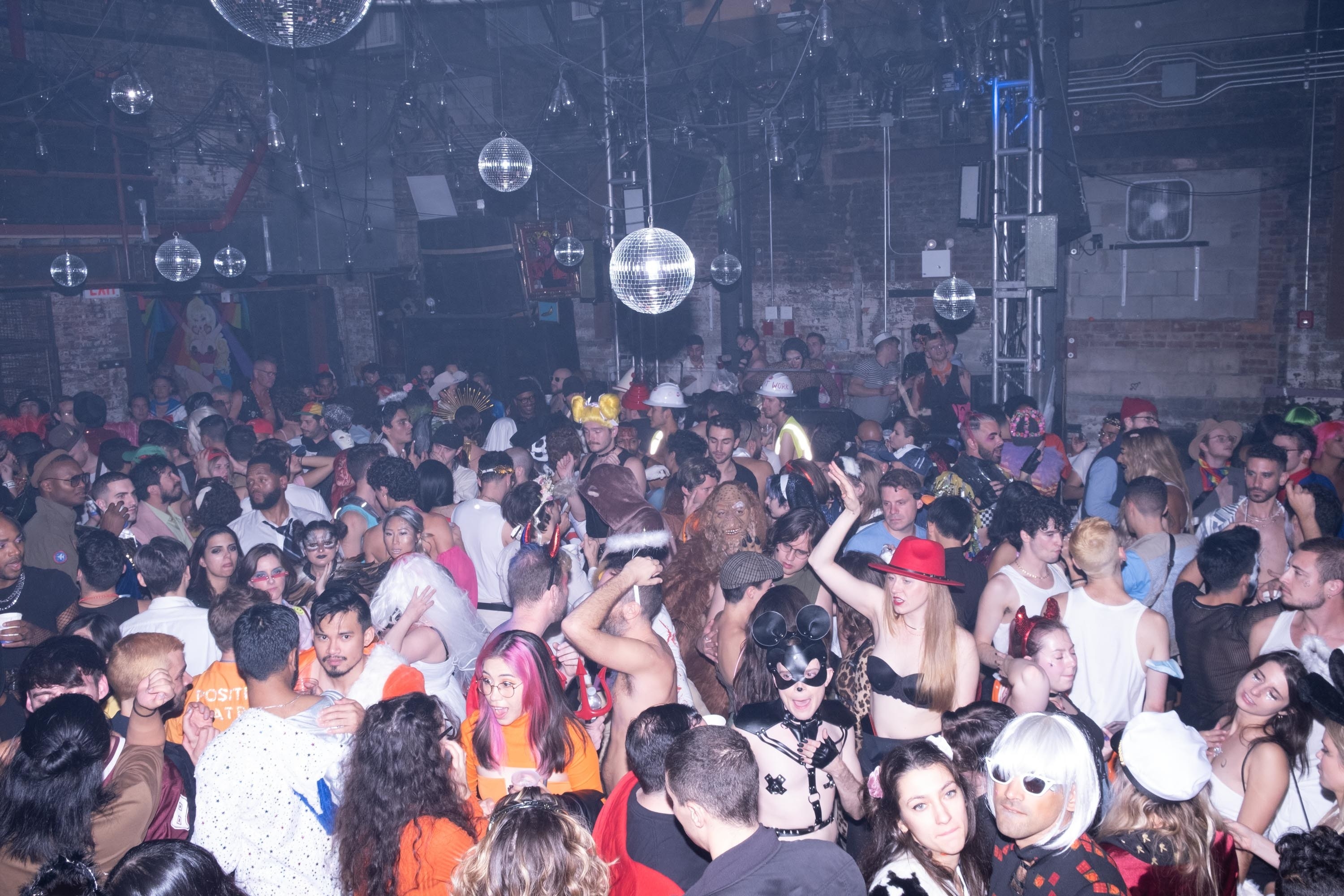 A group of partygoers in a club, with disco balls all around them