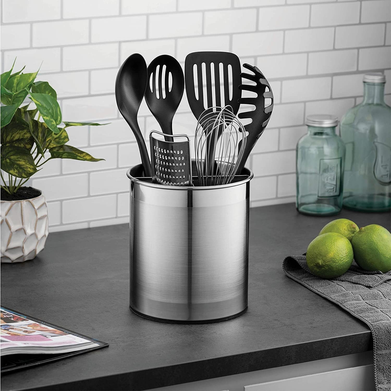 A large metal utensil holder filled with kitchen tools sitting in it