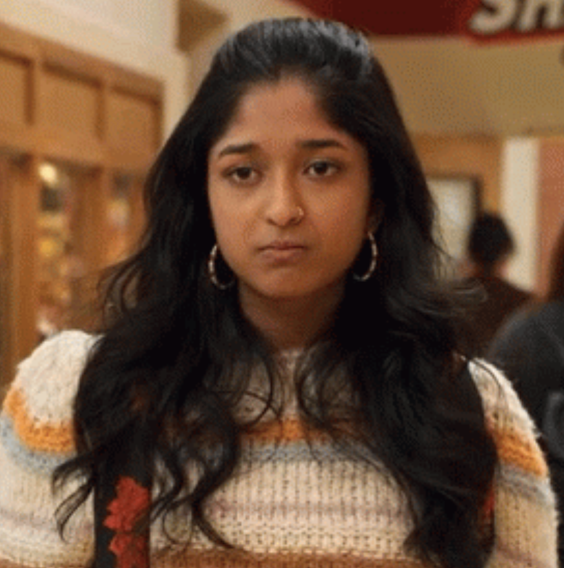 Devi from "Never Have I Ever" making a sad, frustrated face in the school hallway
