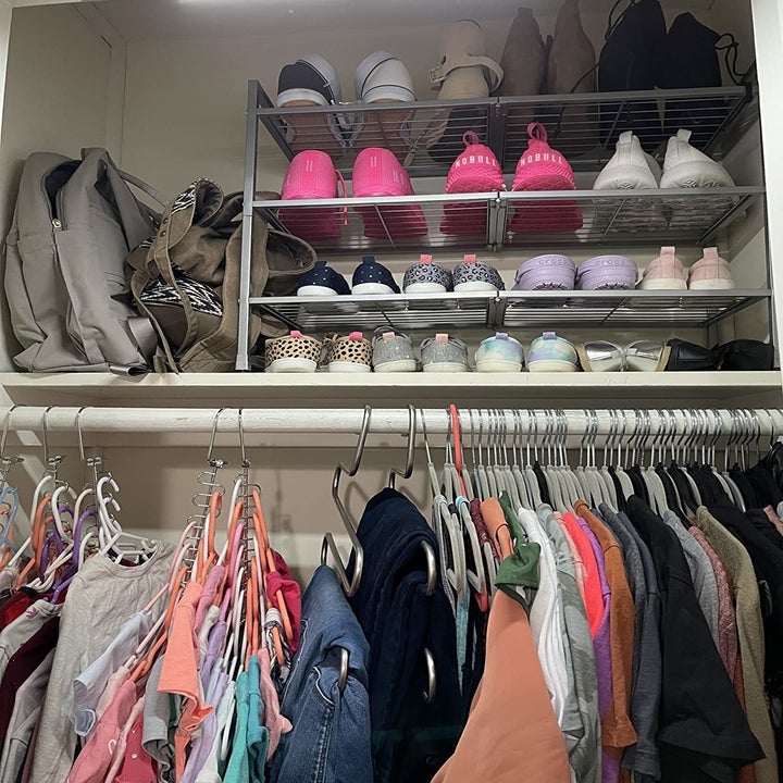 Reviewer photo of the shoe rack placed on the upper shelf of a closet holding many pairs of neatly organized shoes