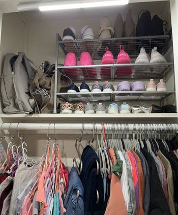 Reviewer photo of the shoe rack placed on the upper shelf of a closet holding many pairs of neatly organized shoes