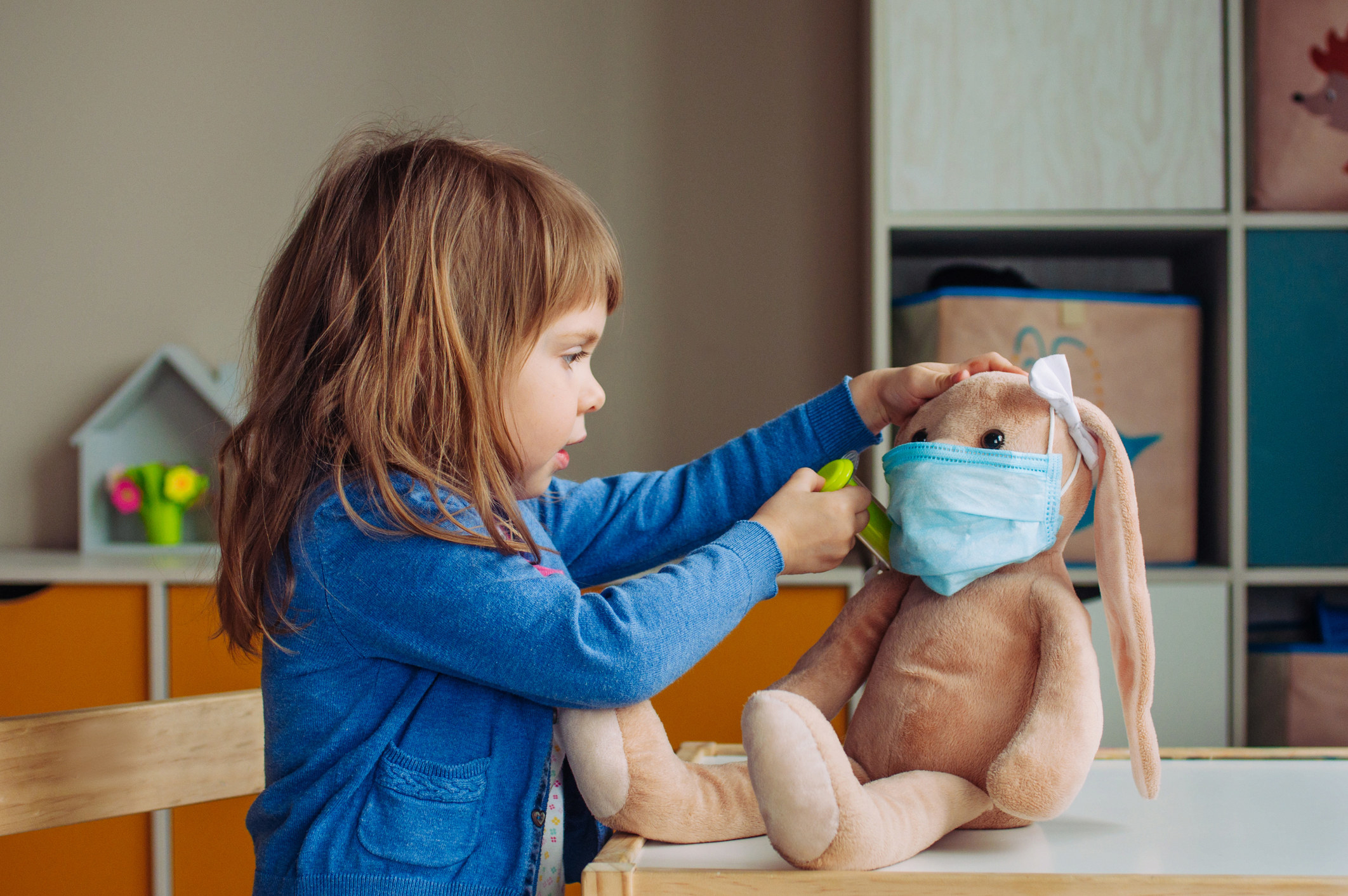 A small child plays doctor with her bunny rabbit toy