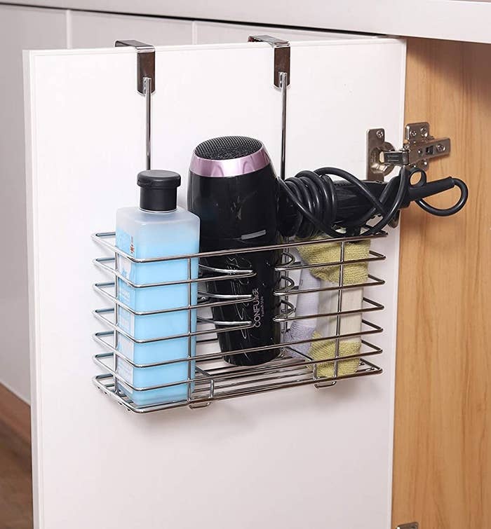 open bathroom cabinet door with wire over the door organizer with hair tools in it